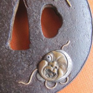 T146. Iron tsuba with Okame and fan